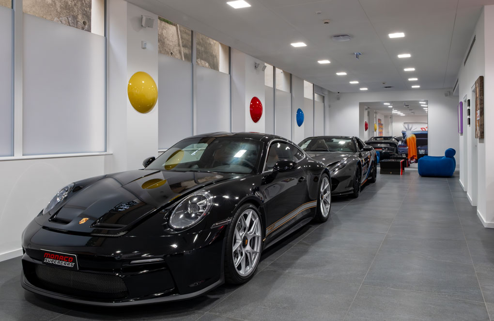 Porsche et véhicules de prestige exposés dans le showroom Monaco Supercars à Monaco